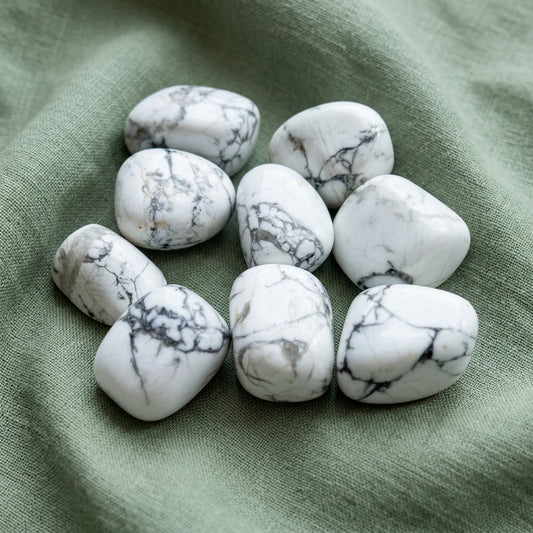 Pietra howlite burattata bianca con venature grigie, appoggiata su un panno