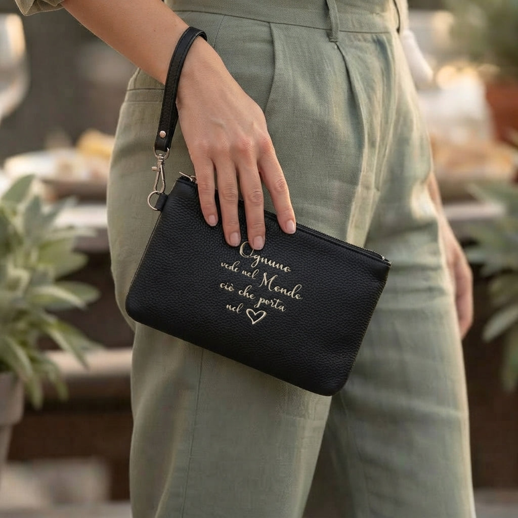 Pochette in ecopelle nera con ricamo "Ognuno vede nel mondo ciò che porta nel cuore" e dettaglio cuore, con polsino, 17x25cm