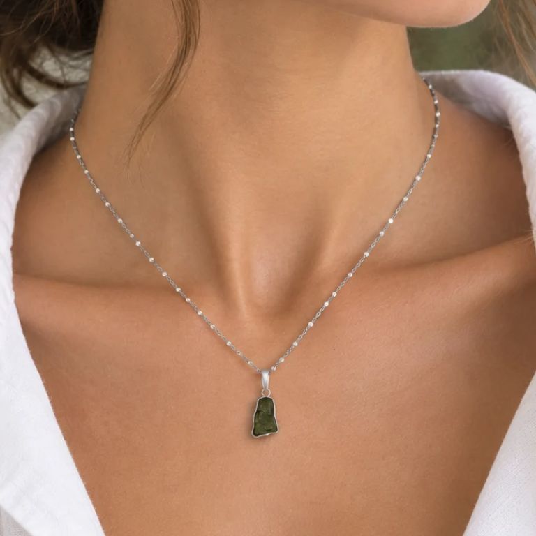 Ciondolo in moldavite grezza verde con castone in argento su catenina, indossato con camicia bianca